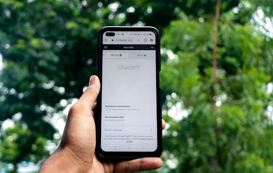 Close-up of a hand holding a smartphone displaying ChatGPT outdoors.