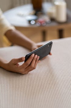 Person's hands holding a smartphone indoors, capturing a vlogging scene.