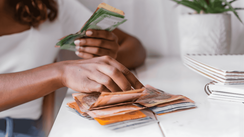 A young woman counting South African rand banknotes